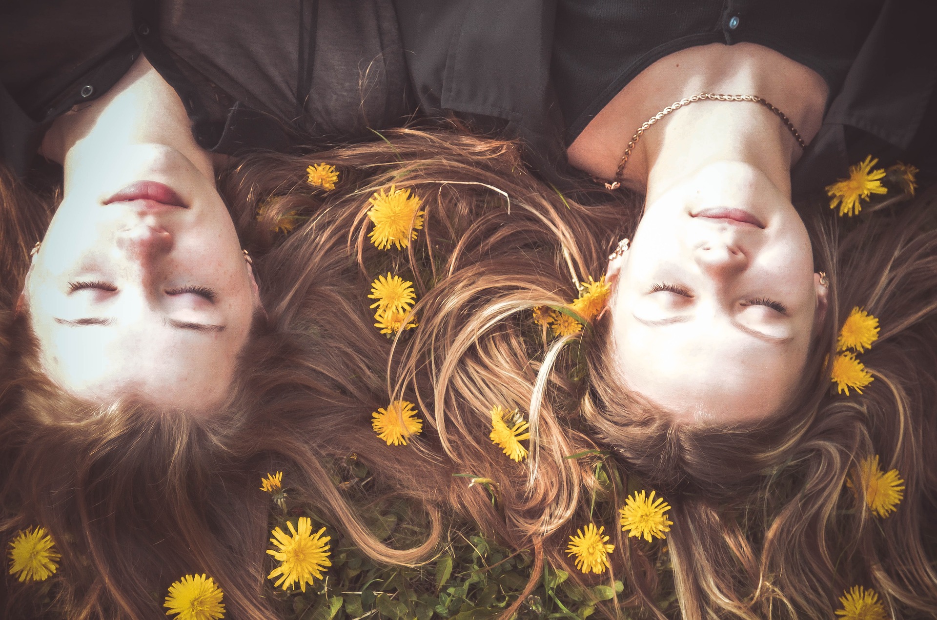 Duas meninas deitadas no chão com flores em volta da cabeça